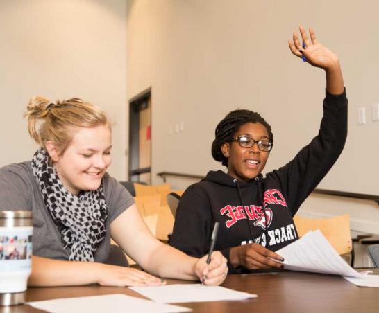 Student raising their hand in a classroom.